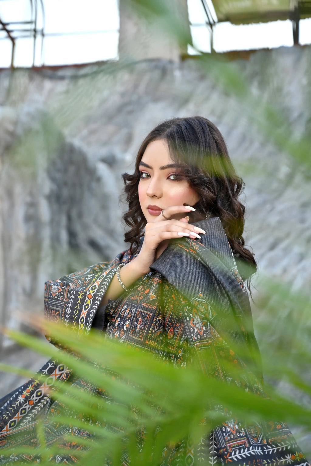 Woman in traditional attire standing among green leaves
